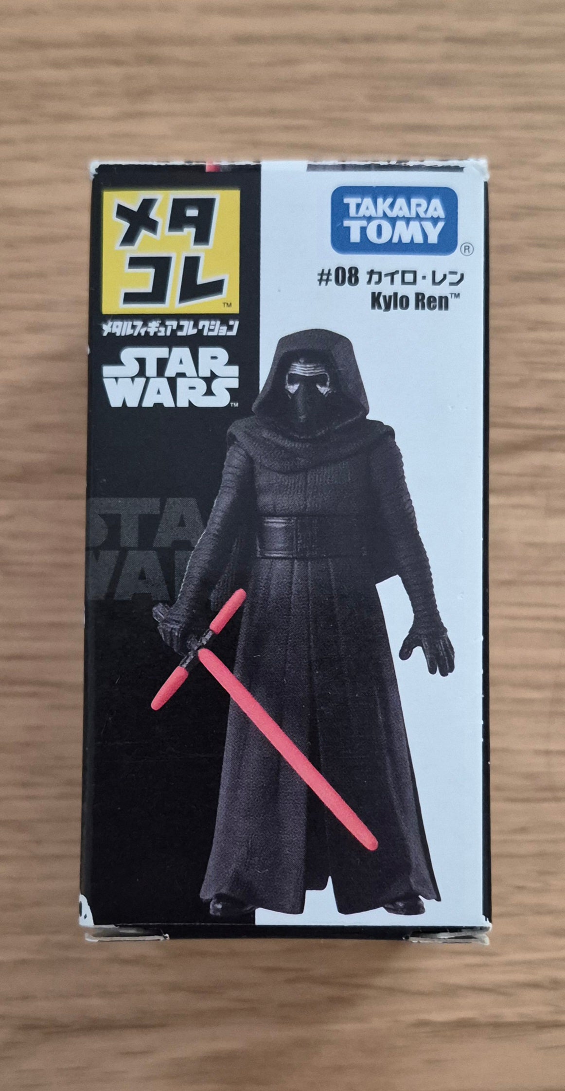 Takara Tomy Star Wars Kylo Ren collectible figure box, featuring Kylo Ren in black robes holding a red lightsaber, on a light wood background.