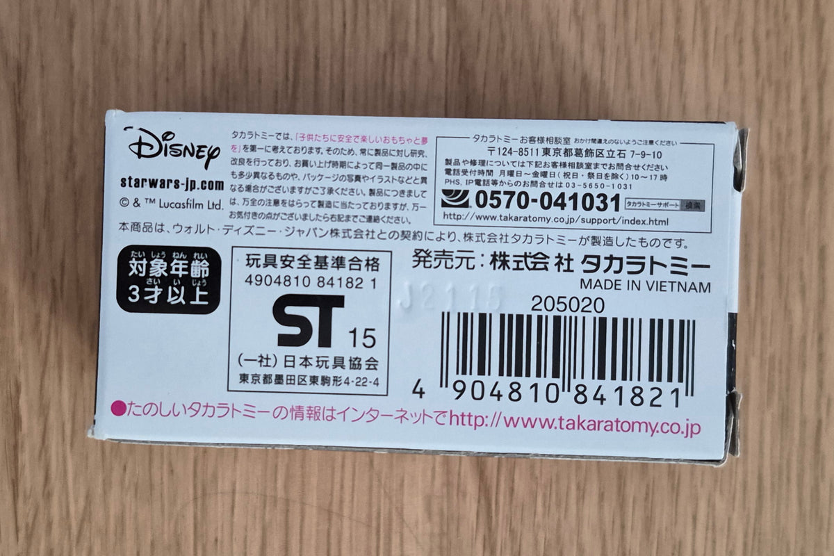 A Japanese Takotome Disney Star Wars toy packaging back card, showing product information, barcode, and warning labels on a light wood background.